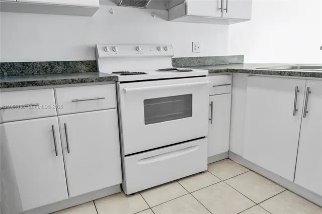 a kitchen with granite countertop white cabinets and white appliances