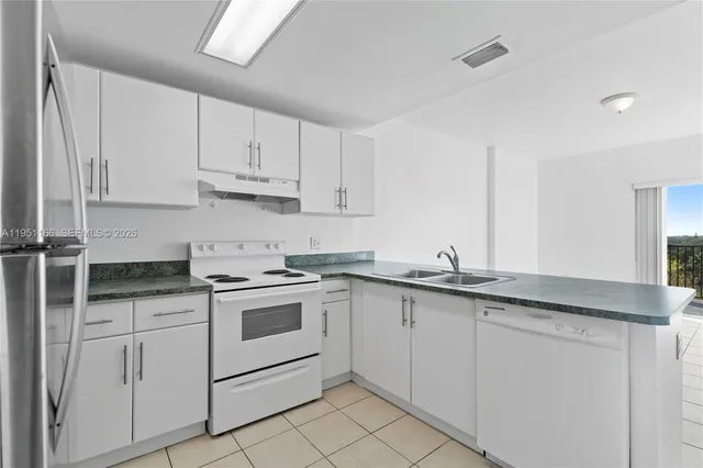 a kitchen with white cabinets sink and appliances