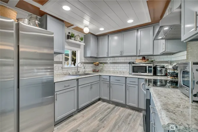 a kitchen with stainless steel appliances granite countertop a sink a stove a refrigerator cabinets and chairs