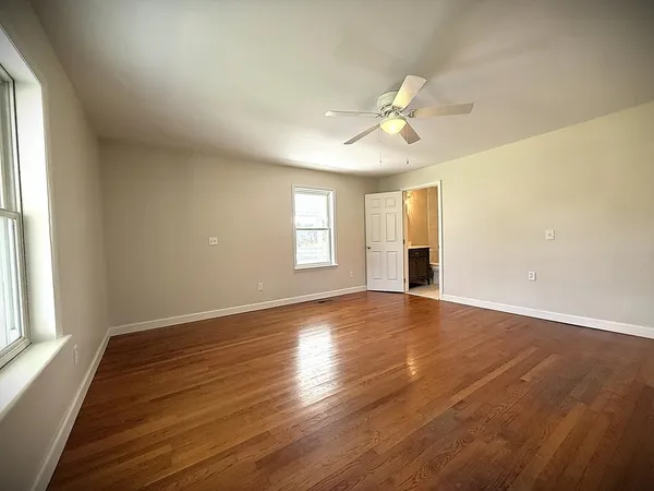 a view of an empty room with a window and wooden floor