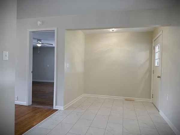 an empty room with wooden floor and a kitchen