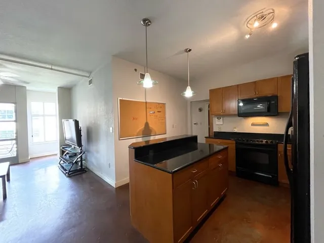 a kitchen with kitchen island granite countertop a stove and a wooden floor