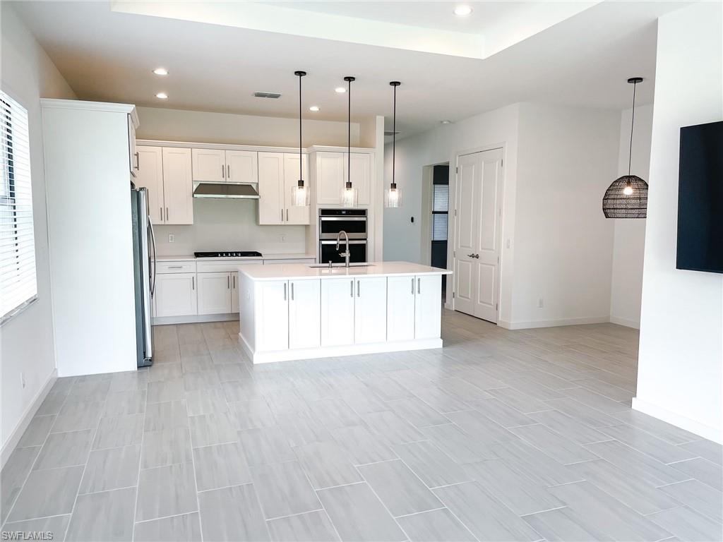 a large white kitchen with cabinets appliances and a wooden floor