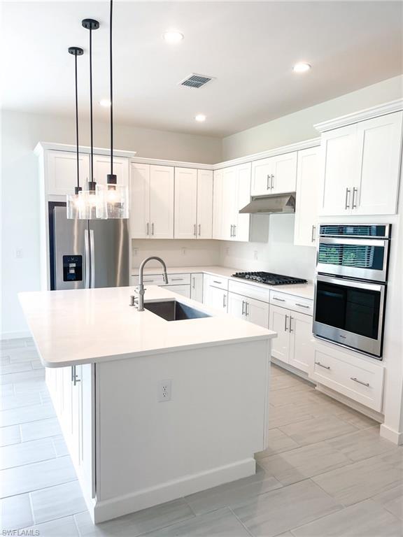 14684 Kingfisher Loop Naples, FL 34120 - Photo 3 of 18 a kitchen with stainless steel appliances kitchen island a sink a counter top space cabinets and a window