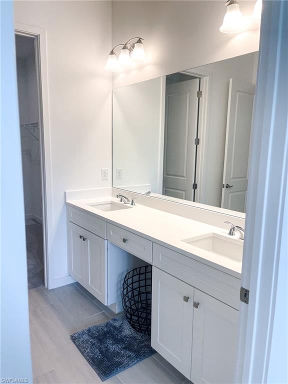 14684 Kingfisher Loop Naples, FL 34120 - Photo 9 of 18 a bathroom with a double vanity sink a mirror and a bathtub