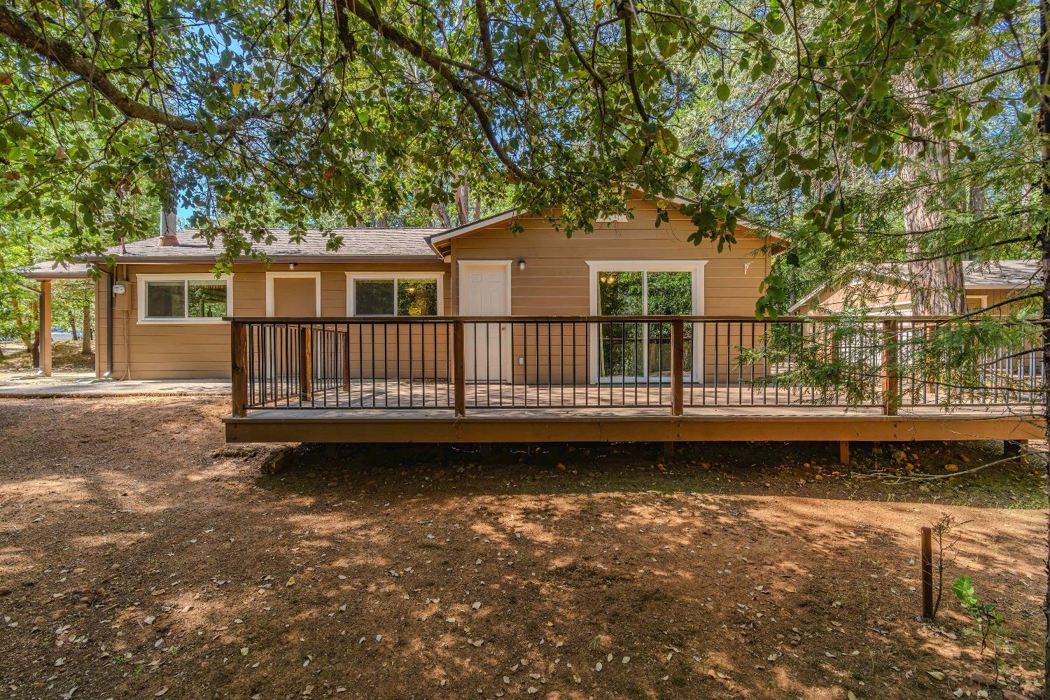 a view of a house with a wooden deck and yard with trees