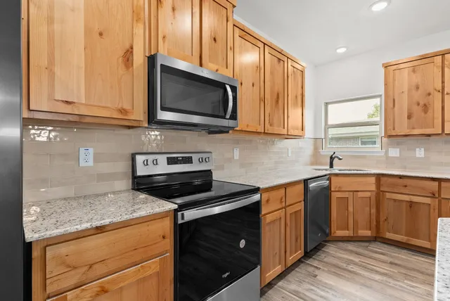 a kitchen with stainless steel appliances granite countertop a stove microwave and sink