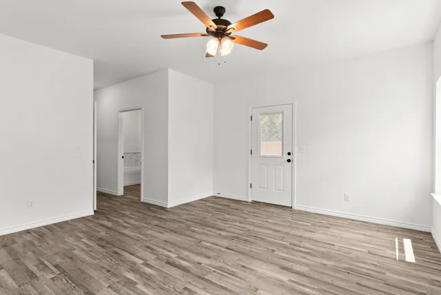 an empty room with wooden floor and a ceiling fan