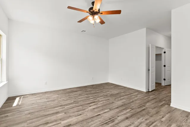 a view of a room with wooden floor and a ceiling fan