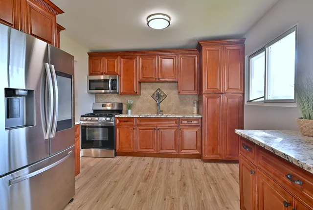 a kitchen with granite countertop a refrigerator stove top oven and sink