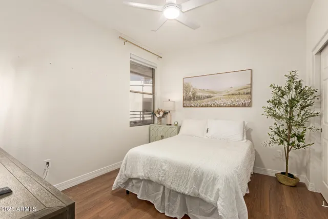 a bedroom with a bed and a potted plant on the dresser