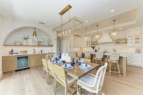 a large kitchen with kitchen island a stove a sink a dining table and chairs with wooden floor