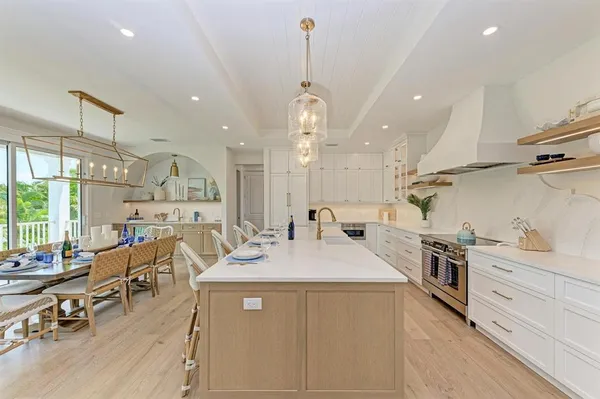 a view of a dining room and livingroom with furniture wooden floor a rug a flat screen tv a rug and a large window