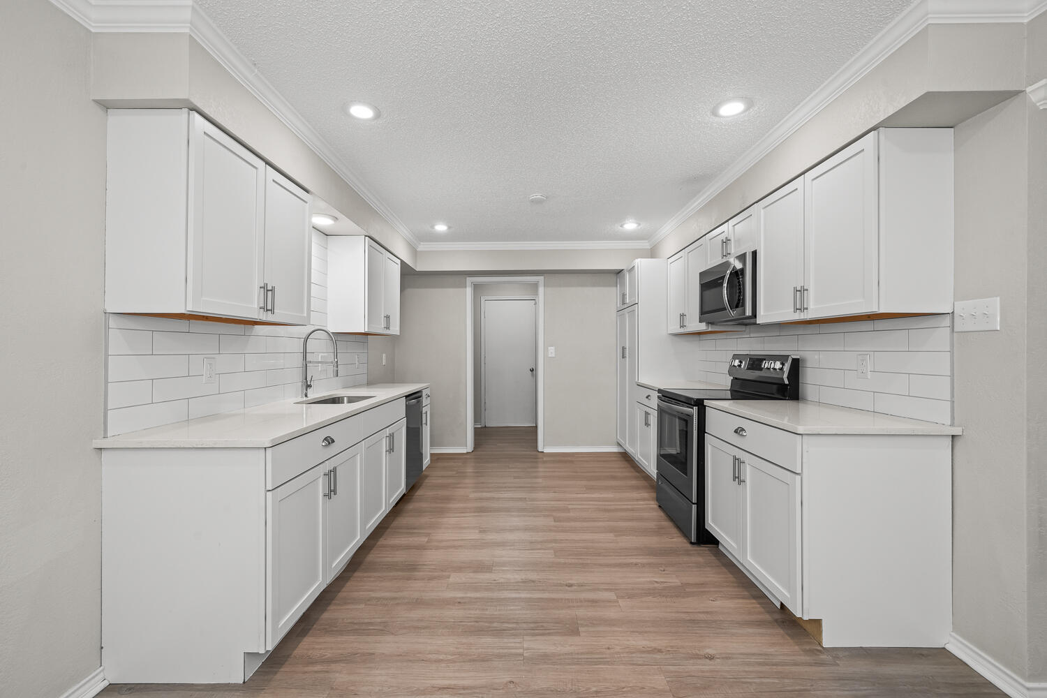 2302 Slide Road, Unit 35 Lubbock, TX 79407 - Photo 13 of 43 a large kitchen with stainless steel appliances granite countertop a stove top oven a sink dishwasher and a refrigerator with wooden floor