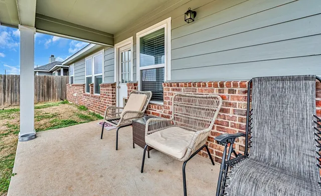 a view of a patio with table and chairs with wooden floor and fence