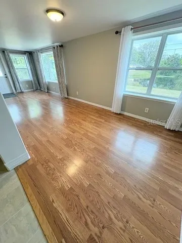 a view of an empty room with wooden floor and a window