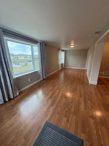a view of empty room with wooden floor and fan