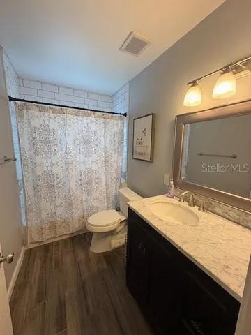 a bathroom with a granite countertop sink toilet and shower