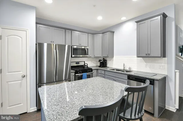 a kitchen with stainless steel appliances granite countertop a kitchen island hardwood floor sink and stove