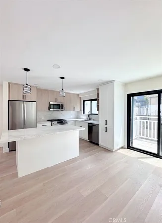 a large white kitchen with kitchen island a stove a sink dishwasher and white cabinets with wooden floor