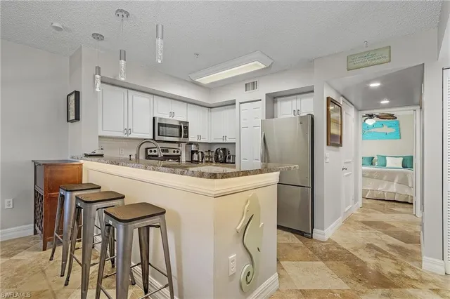 a kitchen with stainless steel appliances a refrigerator stove microwave and white cabinets