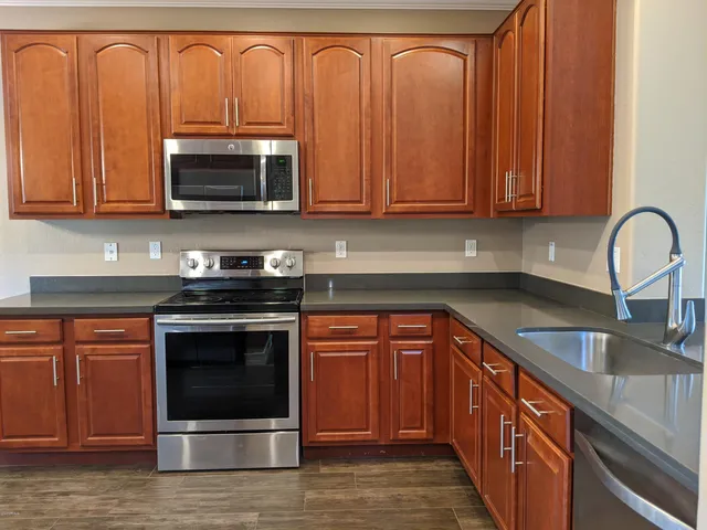 a kitchen with stainless steel appliances granite countertop a stove a sink dishwasher and a microwave oven with cabinets