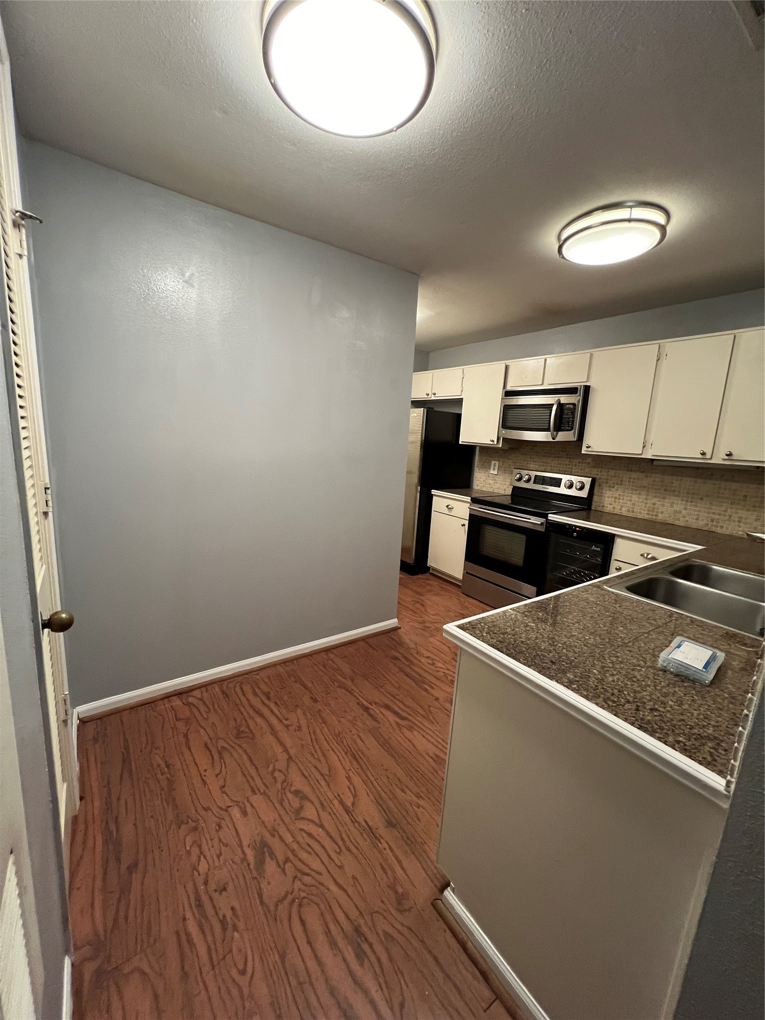 2829 Timmons Lane, Unit 215 Houston, TX 77027 - Photo 10 of 13 a view of a kitchen with wooden floor and stainless steel appliances