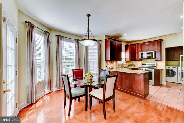 a kitchen with stainless steel appliances granite countertop a stove top oven a sink dishwasher a dining table and chairs with wooden floor