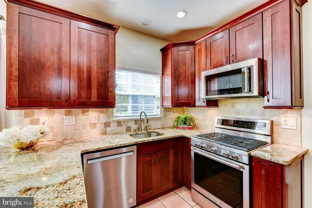 a kitchen with granite countertop a stove top oven microwave and cabinets