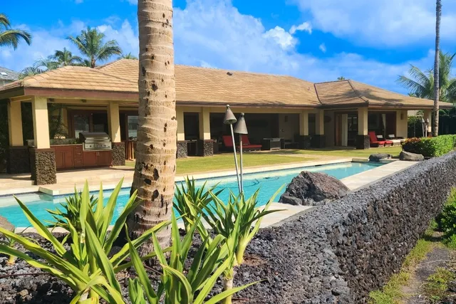 a view of a white house with swimming pool lawn chairs and a yard