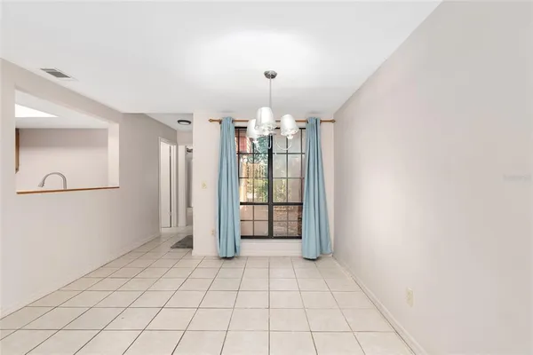 a view of an empty room with window and chandelier