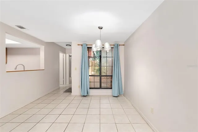 a view of an empty room with window and chandelier