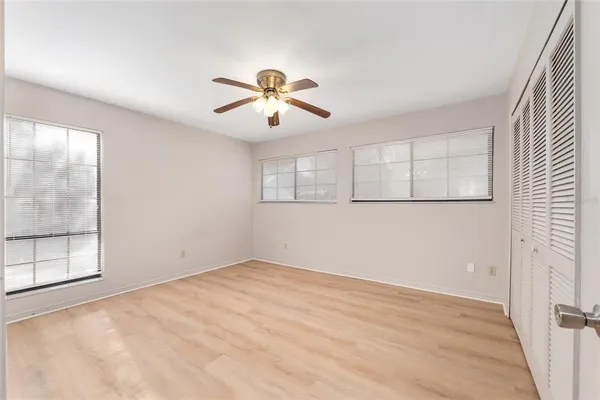 an empty room with windows and chandelier fan