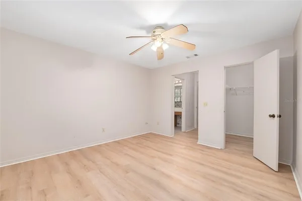 a view of an empty room with wooden floor and a ceiling fan