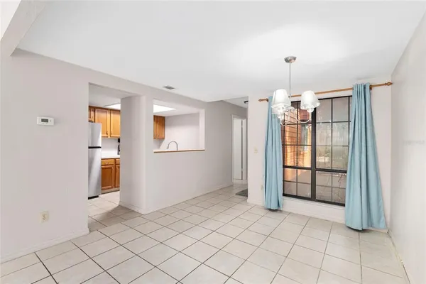 an empty room with chandelier fan and windows