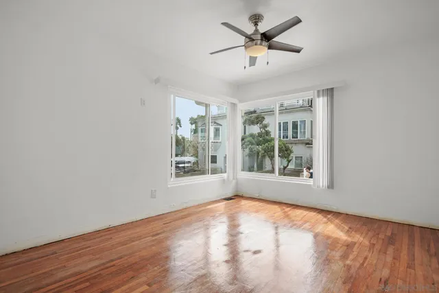 a view of an empty room with a window and wooden floor