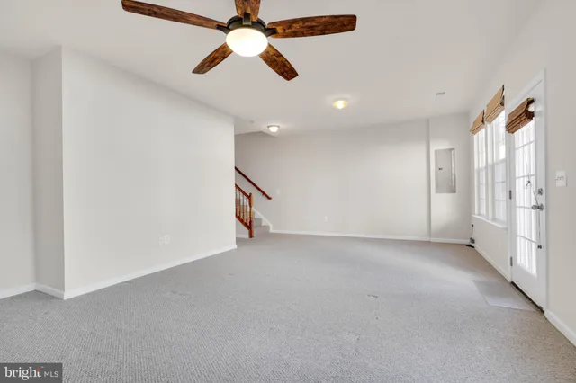 an empty room with chandelier fan and windows