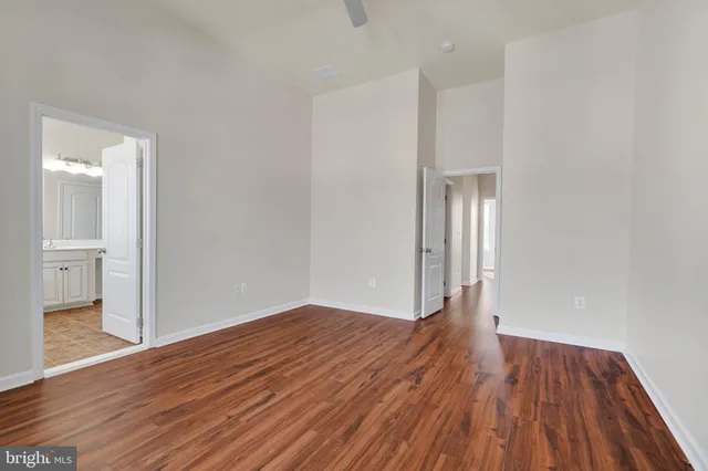 a view of empty room with wooden floor and bathroom