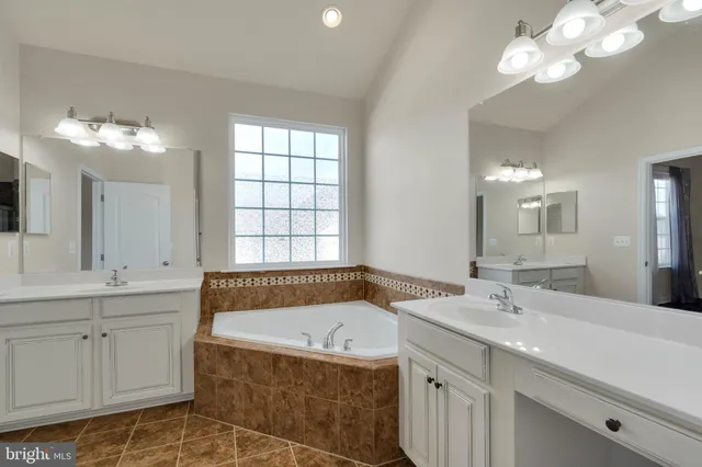 a bathroom with a bathtub a double vanity sink and a mirror