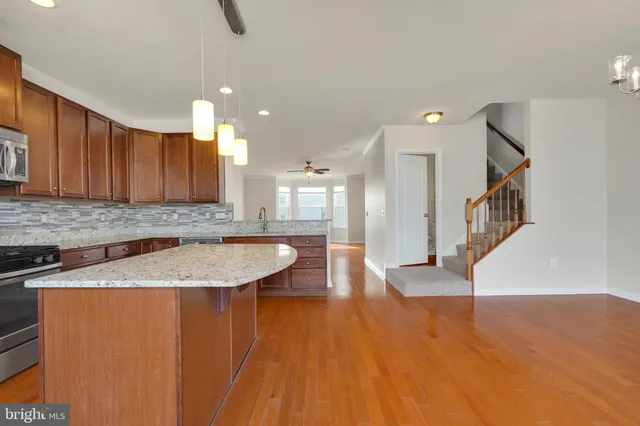 a view of a kitchen with kitchen island a sink wooden floor and counter space