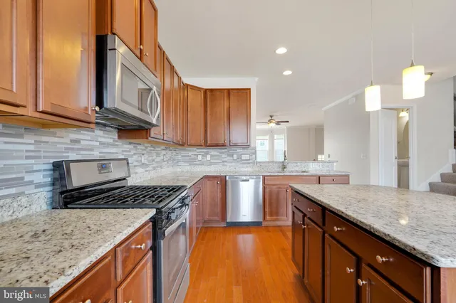 a kitchen with granite countertop kitchen island stainless steel appliances a sink stove and cabinets