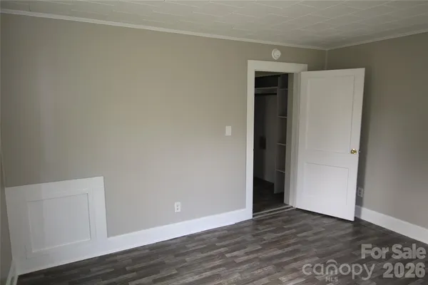 a view of an empty room with wooden floor and closet