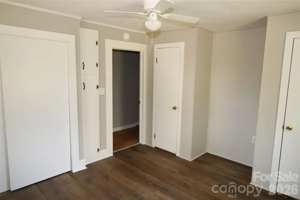 an empty room with wooden floor and fan