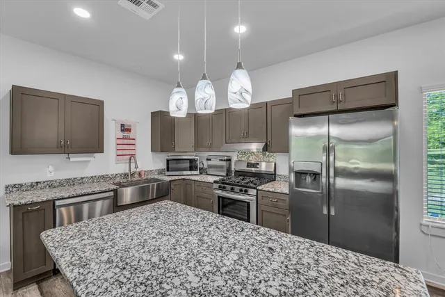 a kitchen with a chandelier a sink stainless steel appliances and cabinets