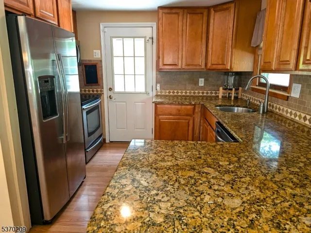 a kitchen with stainless steel appliances granite countertop a refrigerator a stove and a sink