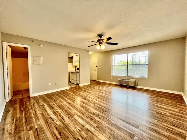 a view of empty room with wooden floor and fan