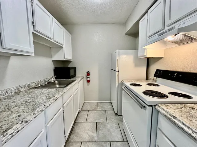 a kitchen with granite countertop cabinets a sink and a stove
