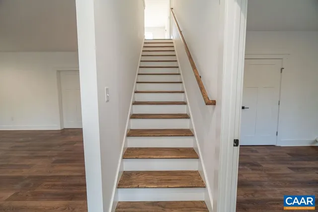 a view of staircase with wooden floor and white walls