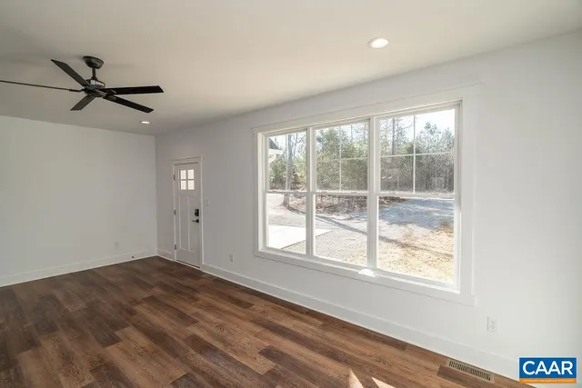a view of an empty room with window and wooden floor