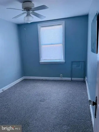 an empty room with a window and a fan